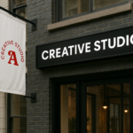 Fachada de agencia creativa con rótulo luminoso y banderola con logotipo, ideal para destacar el branding con productos personalizados.
