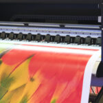 Impresora industrial de gran formato de imprenta online imprimiendo diseño con plumas coloridas en alta resolución