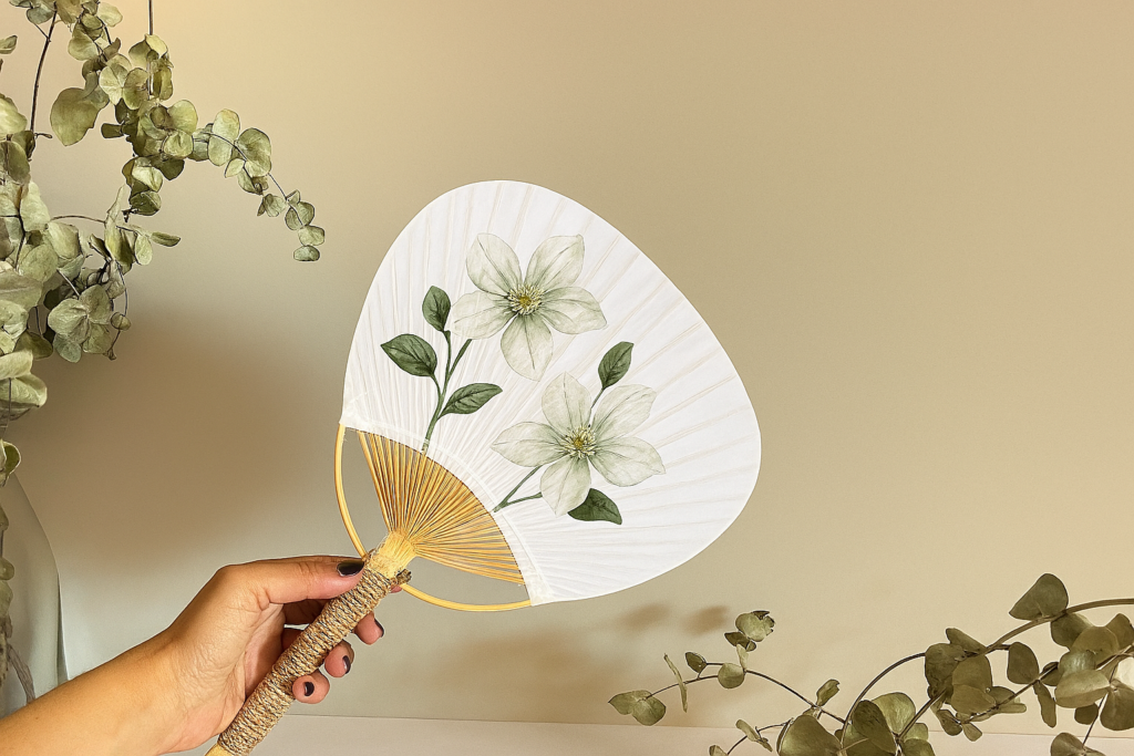 Abanico pai pai artesanal con ilustración de flores verdes y mango de cuerda natural.